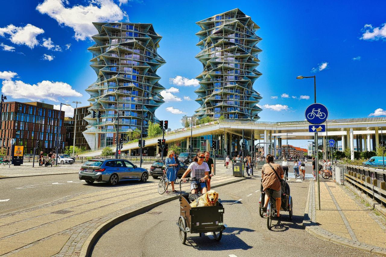 People cycling past modern buildings on a sunny day